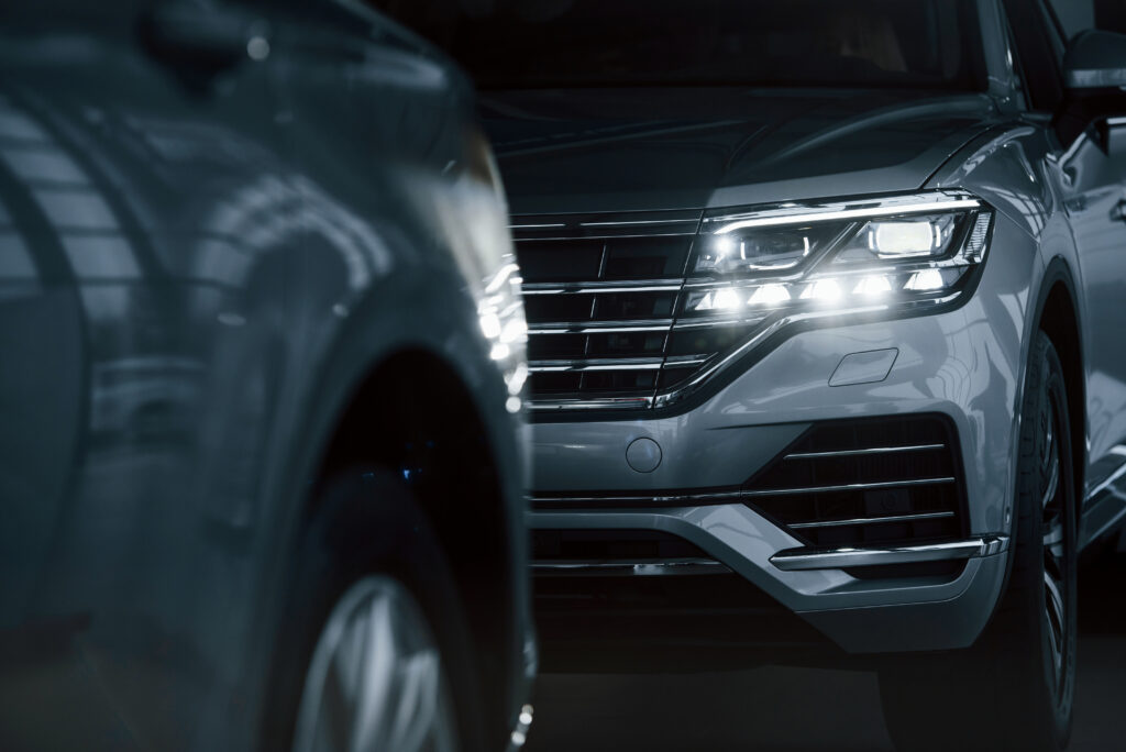 Powerful headlights. Particle view of modern luxury cars parked indoors at daytime.
